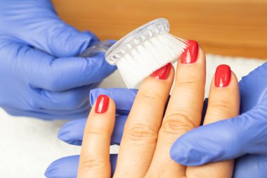 Güzellik salonunda bir fırçayla tırnaklarının altındaki tozu çıkarmak. Manikür, alet, tırnak, prosedür, manikürcü, tıbbi eldiven, oje