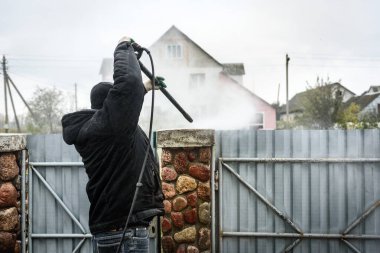 Kirli taş çitleri yüksek basınçlı çamaşır makinesiyle temizlemek.