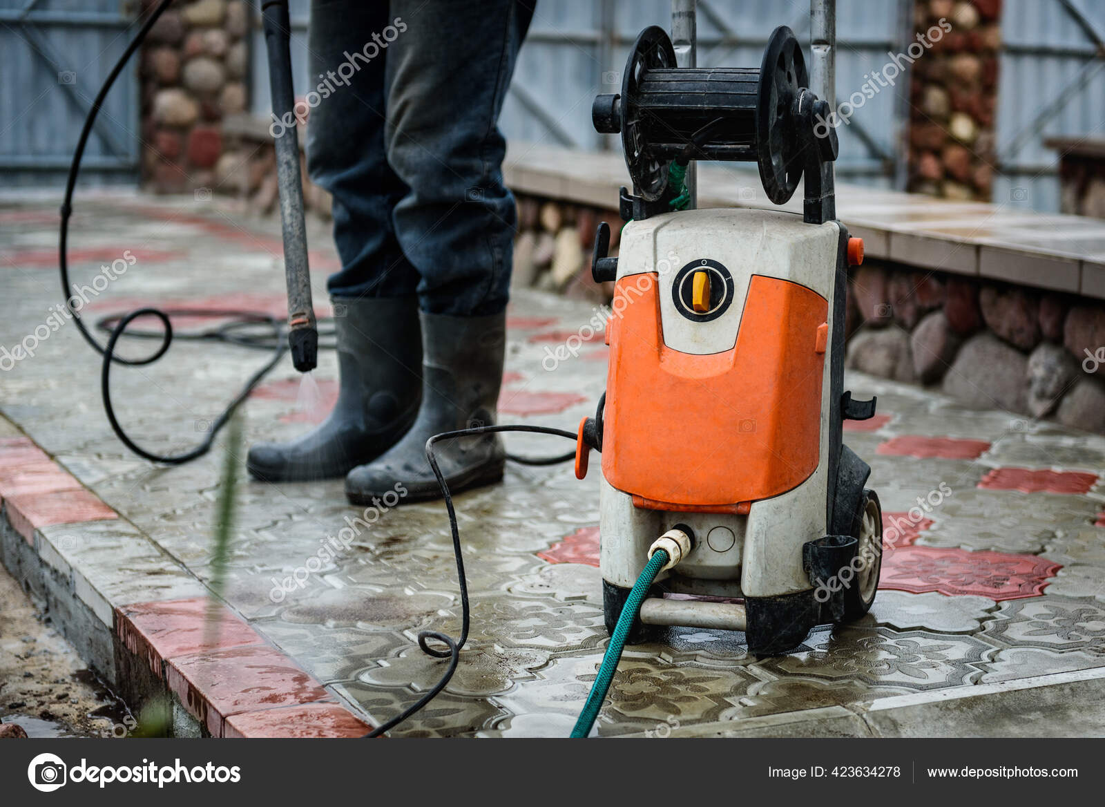 Cleaning paving slab using high pressure power washer. Stock Photo by