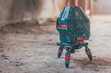 Mavi çalışan lazer seviyesinde inşaat aracı ve duvardaki çizgi.