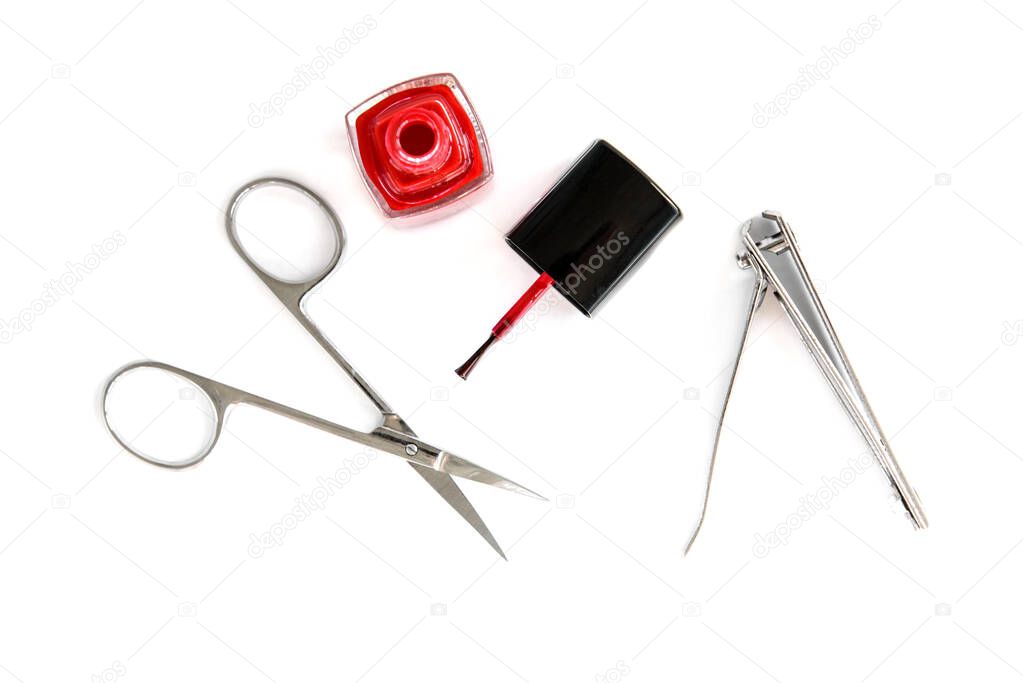 Manicure scissors, forceps and red nail varnish isolated on white background.