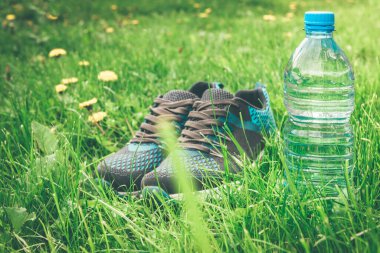 Arka planda bir şişe su ve spor ayakkabısı..