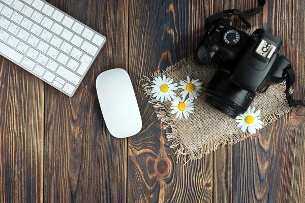 Camera, notebook and field flowers on dark wooden background. Freelance. Earnings in the photo.