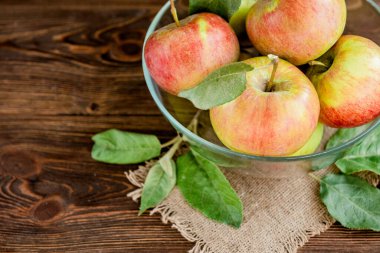 Koyu ahşap arka planda yaprakları olan taze bahçe elmaları. Sonbahar hasadı
