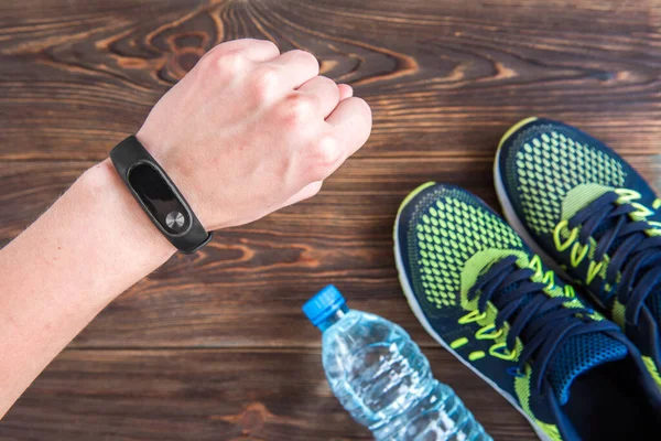 Fitness tracker, smart phone and sneakers on wooden table with copy space. Healthy lifestyle background.