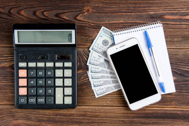 Koyu ahşap arka planda kalemli cep telefonu ve defter..