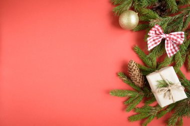 Hediye kutusunun Noel kompozisyonu, köknar dalları, koniler, kırmızı arka planda kırmızı fiyonk..