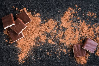 Sütlü çikolata parçacıkları ve siyah arka planda kakao.