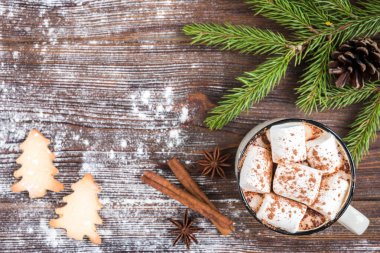 Marşmelovlu bir kupa sıcak çikolata, baharatlar, Noel kurabiyeleri, köknar dalları ve koyu ahşap arka planda koniler. Uzayı metin için kopyala. Noel duvar kâğıdı, kart.