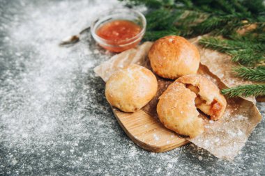 Gri arka planda elma reçeli ile doldurulmuş taze maya çörekleri..