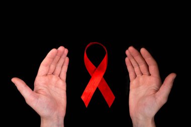 Siyah arka planda el ele tutuşan kırmızı kurdele. HIV, AIDS, madde bağımlılığı ve anoreksiya farkındalığı.