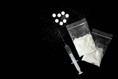 Siyah arka planda şırınga ve beyaz haplar. Uyuşturucu bağımlılığı konsepti. Narkotik. Tedavi