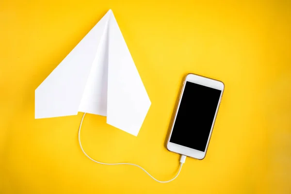 Mobile phone and paper airplane on yellow background. Travel concept. Speed Internet concept.