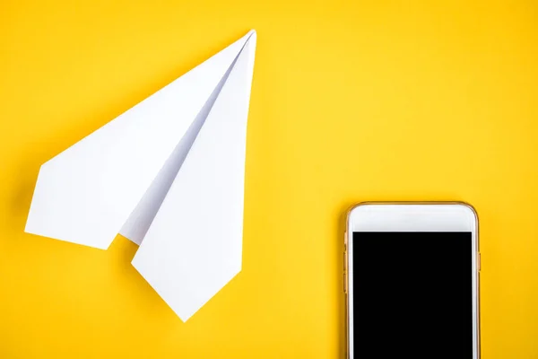 Mobile phone and paper airplane on yellow background. Travel concept. Speed Internet concept.