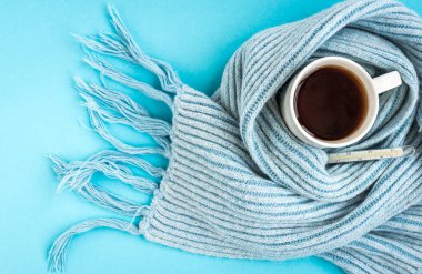 Mavi arka planda mavi eşarplı beyaz fincan çay. Hastalık ve sağlık konsepti.