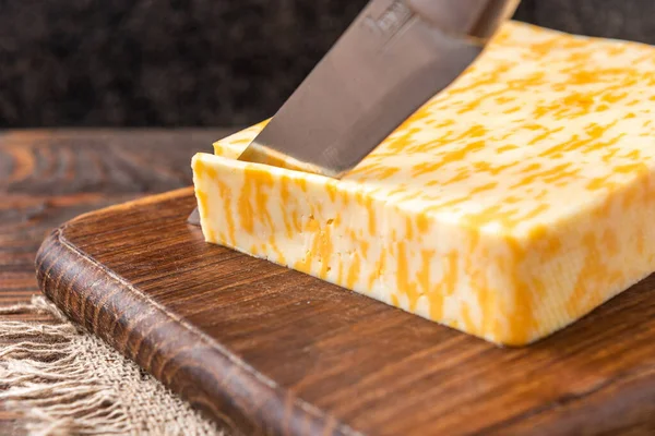 Koyu ahşap arka planda mermer peynir.