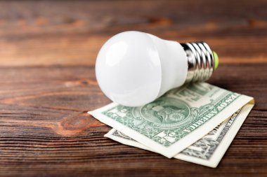 Ampul ve dolar para koyu ahşap arka planda.