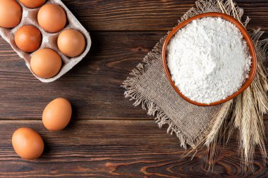 Koyu ahşap masada un ve yumurta. Pişirme arkaplanı.