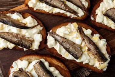 Tahta arka planda sprat, yumurta ve mayonezli sandviç..