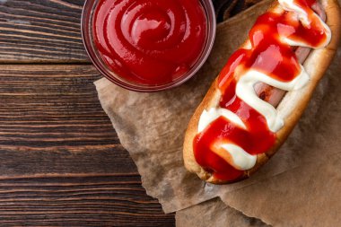 Siyah ahşap arka planda mayonez ve ketçap sosisli sandviç..