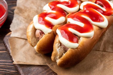 Siyah ahşap arka planda mayonez ve ketçap sosisli sandviç..