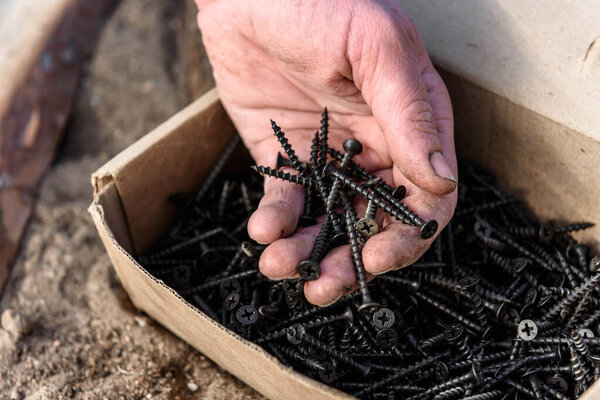 Man takes screws from box.