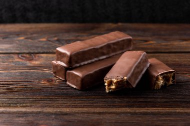 Koyu ahşap arka planda karamel ve fıstıklı çikolata..