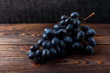 Koyu tahta arka planda mavi üzümler.