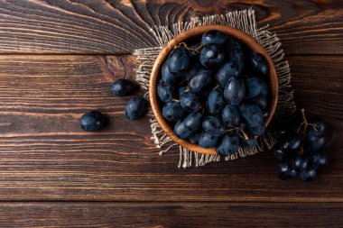 Koyu tahta arka planda mavi üzümler.