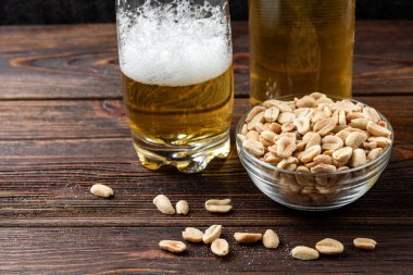 Koyu ahşap arka planda tuzlu fıstık birası..