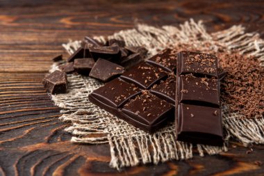 Chocolate bar and cocoa on dark wooden background.