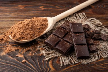 Chocolate bar and cocoa on dark wooden background.