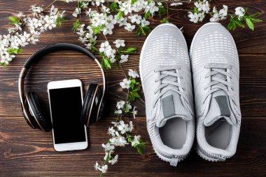 Bahar çiçeği dalı, siyah ahşap arka planda spor ayakkabılar ve kulaklıklar. Bahar fitness ve spor.