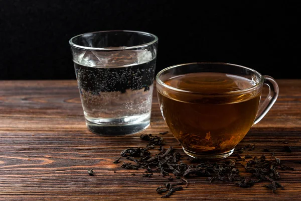 濃い木の背景に紅茶と水のカップ — ストック写真