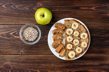 Ayçiçeği tohumlu yulaf krepi ve yeşil elmalı koyu ahşap zemin üzerinde muz..