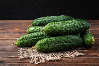 Koyu ahşap arka planda salatalıklar.