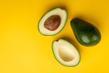 Sarı arka planda avokado meyvesi.