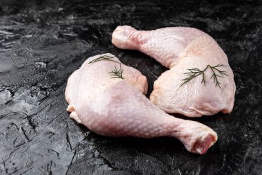 Siyah arka planda çiğ tavuk bacağı.