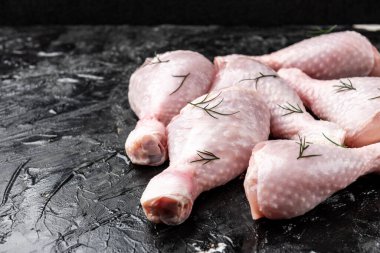 Siyah arka planda çiğ tavuk bacağı.