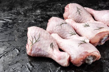 Siyah arka planda çiğ tavuk bacağı.