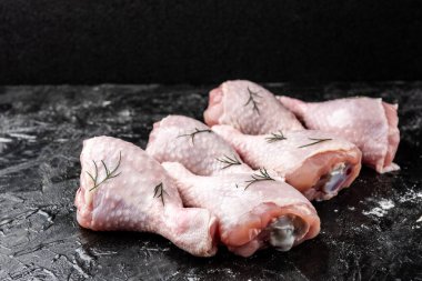 Siyah arka planda çiğ tavuk bacağı.