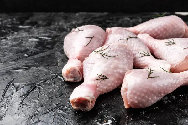 Siyah arka planda çiğ tavuk bacağı.