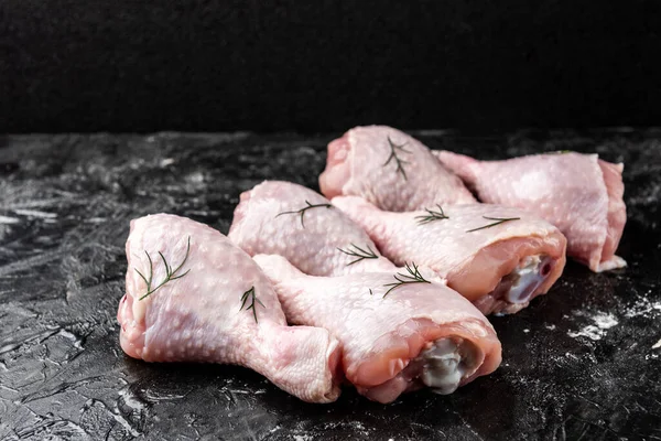 Siyah arka planda çiğ tavuk bacağı.