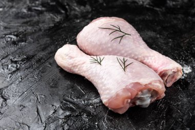 Siyah arka planda çiğ tavuk bacağı.