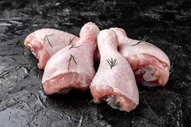 Siyah arka planda çiğ tavuk bacağı.