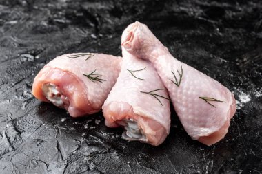 Siyah arka planda çiğ tavuk bacağı.