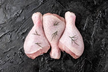 Siyah arka planda çiğ tavuk bacağı.