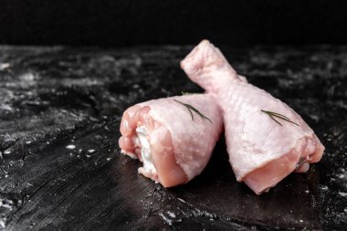 Siyah arka planda çiğ tavuk bacağı.