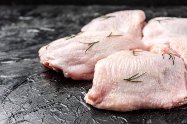 Siyah arka planda çiğ tavuk budu..