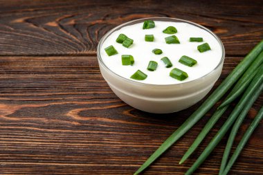 Koyu ahşap arka planda yeşil soğanlı ekşi krema..